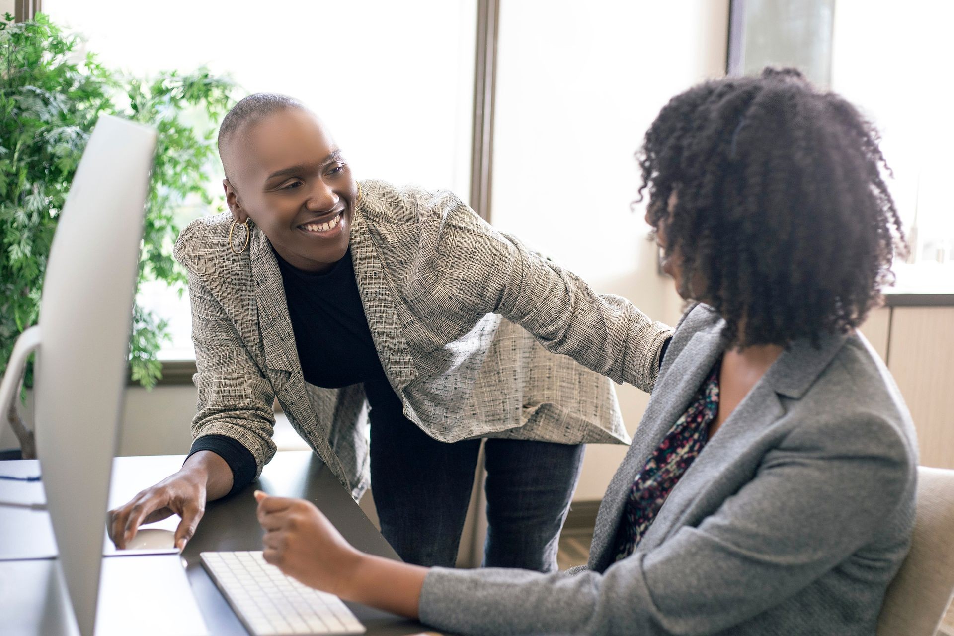 Black African American businesswomen or coworkers together in an office doing teamwork or job training. The women are working together at a startup business.